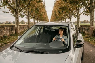 Une jeune femme au volant d'une voiture d'auto-école en Maine-et-Loire, sur une route bordée d'arbres typique de la région