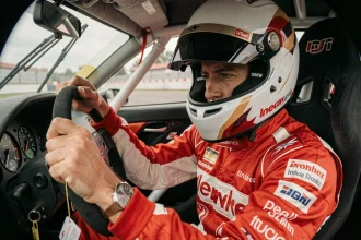 Pilote concentré en combinaison de course au volant d'une voiture sur circuit de pilotage lors d'un stage vitesse